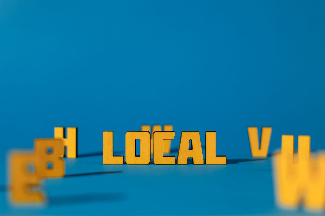 Abstract image featuring yellow wooden letters spelling LOCAL on a blue background, offering ample copy space.